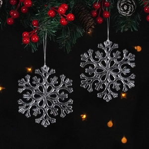 Clear plastic snowflake ornaments hanging on pine branches with berries and lights