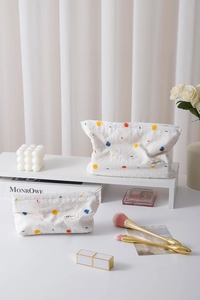 Detailed view of white cotton makeup bag featuring colorful abstract dot embroidery