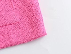 Detail of bright pink knit texture showing high-quality stitching on a stylish cardigan