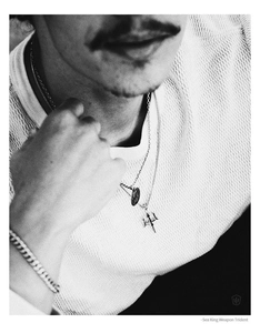 Detail of trident pendant and circular medal necklace layered with Cuban link bracelet