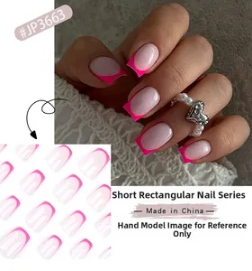 Close-up of short square fake nails with pink French tips design on hand and packaging