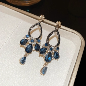 Macro detail of vintage teardrop earrings with blue crystals and tassels in a gift box