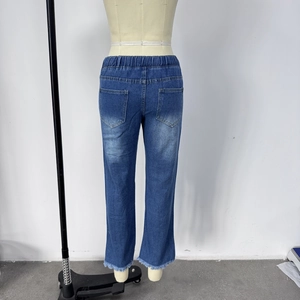 Detail view of elastic high waist and distressed frayed hem on blue denim jeans