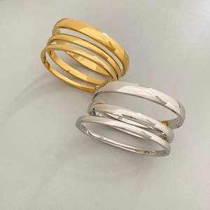 Close-up of stacked gold and silver minimalist stainless steel bracelets with mirror polish