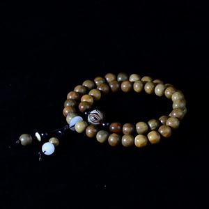 Macro detail of natural green sandalwood beads with lotus charms and wood grain texture