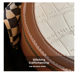 Detail of crocodile pattern leather bag with contrast stitching and checkerboard silk scarf