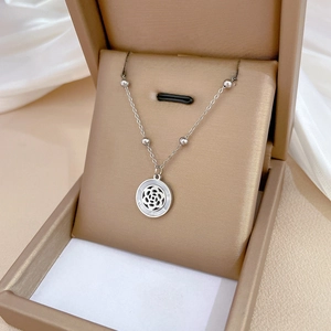 Macro detail of silver camellia pendant with geometric shell pattern in a jewelry box
