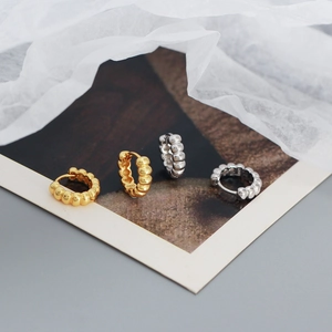 Artistic layout of S925 sterling silver hoop earrings with a beaded texture on paper