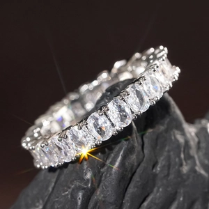 Classic oval cut eternity ring with sparkling stones on silver band displayed on black stone