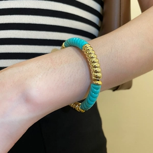 Detail of turquoise and gold spiral acrylic beads on a geometric fashion bracelet