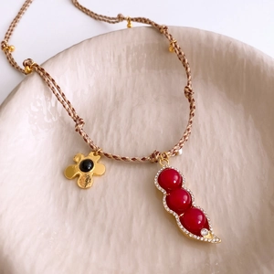 Detail of vintage beaded necklace with gold flower and red pod pendants on woven cord
