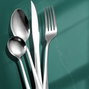 Polished stainless steel cutlery set with flatware on dark marble background