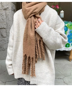 Detail of soft brown cashmere-like scarf with thick knit texture and long fringes