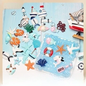 Macro detail of resin ocean theme charms featuring starfish, lighthouse and sailboats