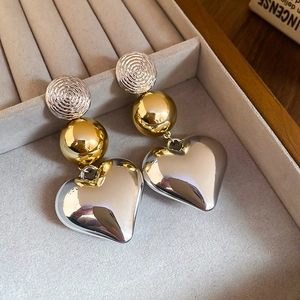 Detail shot of mixed metal heart drop earrings on a premium grey velvet jewelry tray