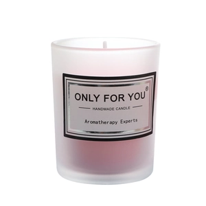 Handmade pink soy wax aromatherapy candle in a frosted white glass jar on white background