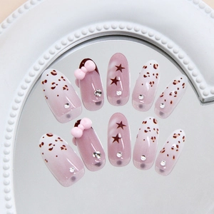 Pink leopard print press-on nails with 3D bows and star patterns on a mirror tray