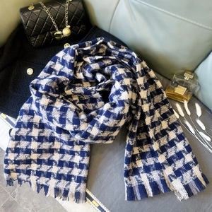 Macro detail of navy and cream houndstooth scarf with long fringe and thick knit texture