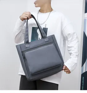 Gray waterproof nylon business tote bag with spacious front zipper pocket held by model