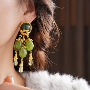 Close-up of vintage olive green fringe earrings with golden metal details on a model