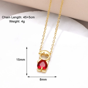 Gros plan détaillé d'un collier doré avec pendentif garçon et zircon rouge en forme de cœur