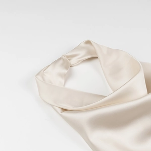 Close-up of beige satin fabric texture and 3D floral detail on elegant halter dress