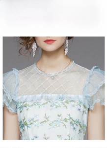 Détail de la robe bleu clair montrant la broderie florale et l'encolure en tulle