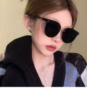 Close-up of oversized rimless black sunglasses with silver metal bridge on model