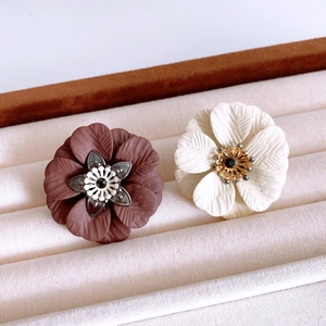 Detailed close-up of brown and cream flower jewelry pieces on a beige velvet display case