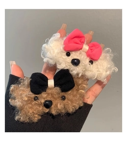 Close-up of plush puppy hair clips with pink and black bows in white and brown fur