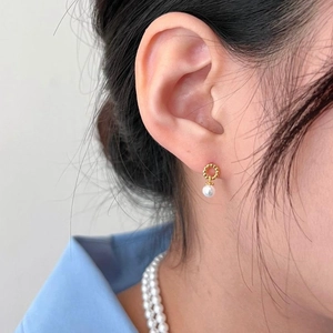 Elegant twisted gold hoop earrings with white pearls for a minimalist aesthetic look