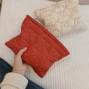 Detailed rabbit-pattern quilted makeup bag showing red fabric texture and label