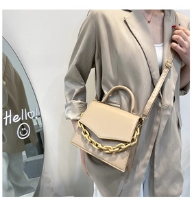 Detail of a beige crossbody bag featuring a bold yellow decorative chunky chain strap