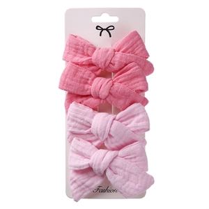 Set of four textured pink fabric bow hair clips for kids on white display card