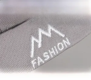 Macro shot of embroidery featuring a mountain icon and FASHION text on a gray knit cap