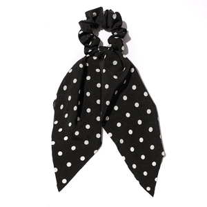 Black fabric hair scrunchie with white polka dots and a large decorative bow