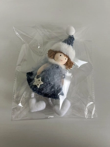 Close-up of a Christmas angel doll with blue knitted dress and white star detail in package