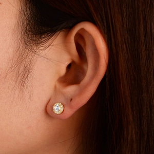 Close-up of golden halo stud earring with central round zircon on woman's ear