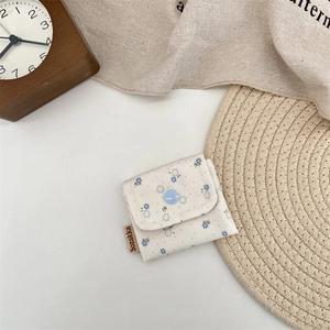 Detailed close-up of a floral cotton coin purse with blue patterns and a button closure