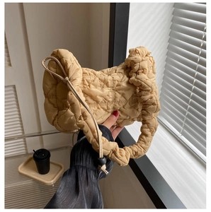 Detail of beige quilted puffer bag with soft diamond texture and ruffled shoulder strap