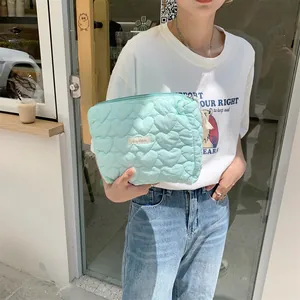Detail of mint green quilted heart pattern makeup bag with woven brand label