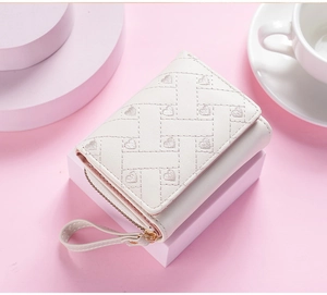 White short wallet detail showing embroidered heart pattern and fine zipper pocket craftsmanship.