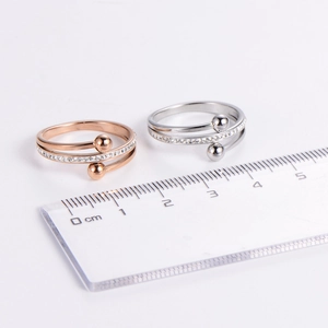 Minimalist crisscross rings in rose gold and silver with zircon accents on white background