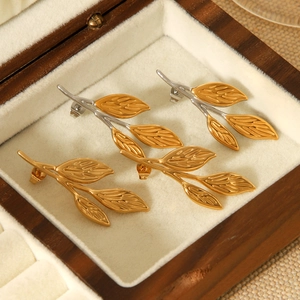 Detailed view of gold and silver leaf earrings in a premium wooden jewelry box