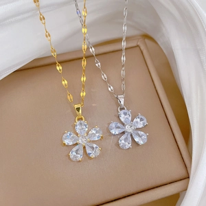 Elegant gold and silver titanium flower necklaces with sparkling crystals on beige box