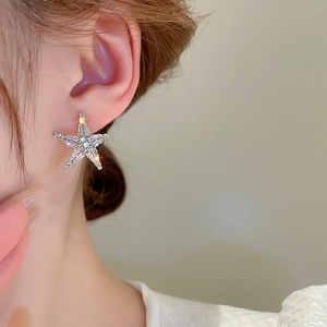 Close-up of star-shaped crystal stud earring with sparkling zircons worn by a model