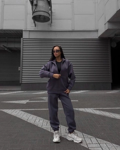 Detail of purple zip-up hoodie and high-waist joggers set on model in urban street setting