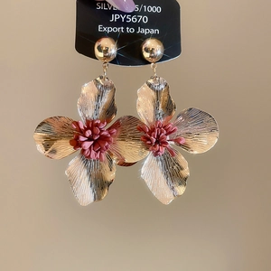 Detailed macro of gold-plated flower earrings with velvet pink centers and 925 silver pins