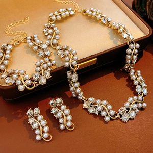 Flat lay of vintage gold jewelry set featuring oval pearls and diamonds on leather