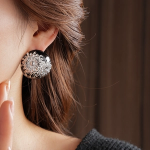 Close-up of vintage round floral earrings worn on ear showing elegant retro style